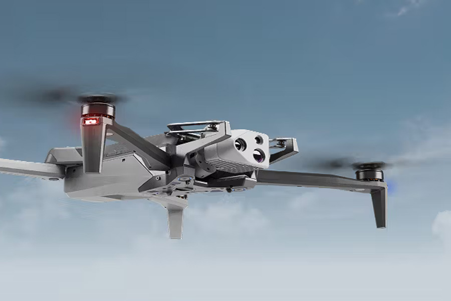 A drone flying against a blue sky with clouds in the background.